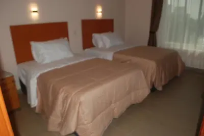 a hotel room with two beds and a window at Atlas Hotel in Arusha