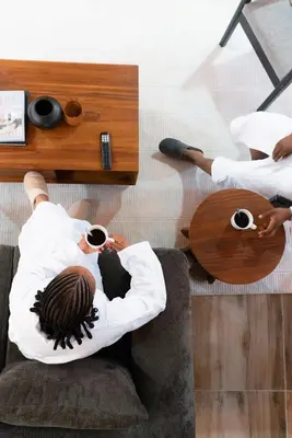 two people sitting on a couch with cups of coffee at Starico Residence in Nkoanrua