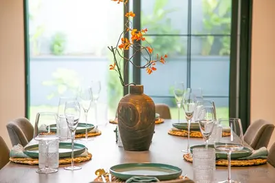 a table with a vase and plates and glasses at Modern Farmhouse & French Elegance Stay for 6 in Arusha