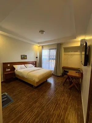 a bedroom with a bed and a desk and a television at Boma masai Garden in Boma la Ngombe