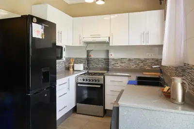 a kitchen with white cabinets and a black refrigerator at Kobe House in Olturoto