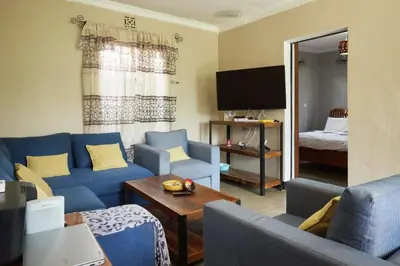 a living room with blue couches and a bedroom at Kobe House in Olturoto
