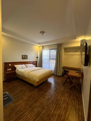 a bedroom with a bed and a desk and a television at Boma masai garden in Boma la Ngombe