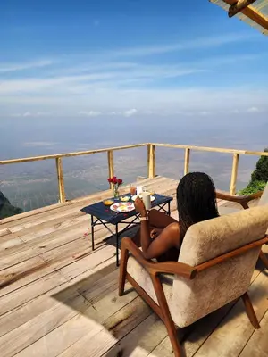 a woman sitting in a chair on a deck with a table at Shume cliffs in Manga