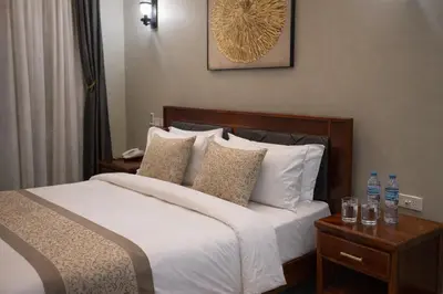 a bedroom with a bed with white sheets and pillows at Peak Hotel & Safaris in Karatu