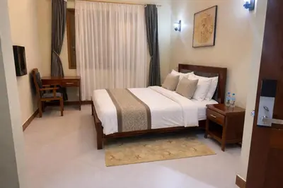 a bedroom with a bed with a desk and a window at Peak Hotel & Safaris in Karatu