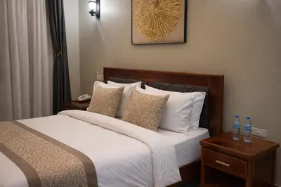 a bedroom with a bed with white sheets and pillows at Peak Hotel & Safaris in Karatu