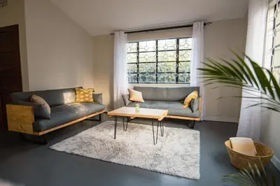 a living room with two couches and a table and a window at Open Gate House in Arusha