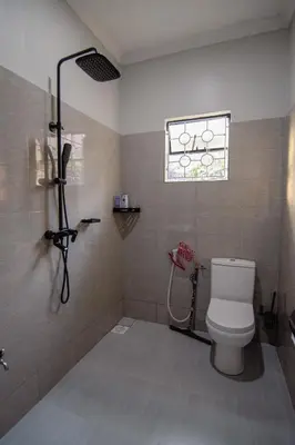 a bathroom with a shower with a toilet and a window at Open Gate House in Arusha