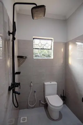 a bathroom with a toilet and a shower with a window at Open Gate House in Arusha