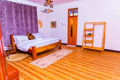 a bedroom with a bed and a wooden floor at Kaya homestay in Zame