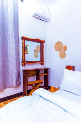 a bedroom with a bed and a table and a mirror at Kaya homestay in Zame