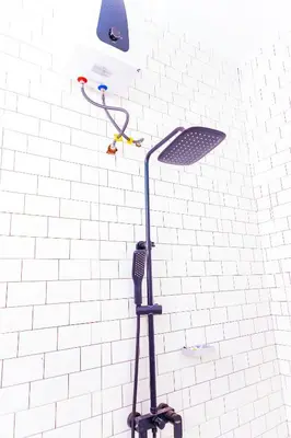 a shower head on a white tiled wall at Kaya homestay in Zame