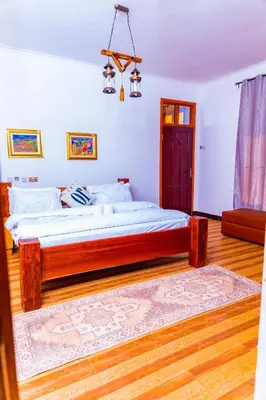 a bedroom with a large bed with a wooden frame at Kaya homestay in Zame