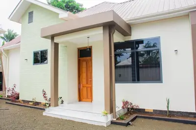 a small white house with a brown door at KiliView Homestay in Moshi