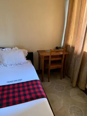 a bedroom with a bed and a table and a chair at Golden View Hotel in Moshi