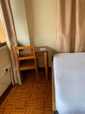 a bedroom with a desk and a bed and a chair at Golden View Hotel in Moshi