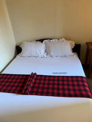 a bed with a red and black plaid blanket on it at Golden View Hotel in Moshi