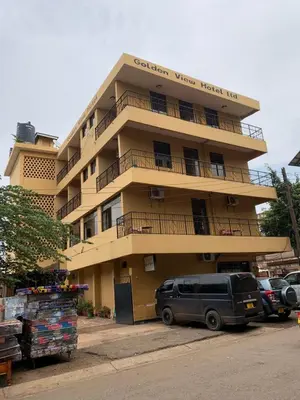 a tall building with cars parked in front of it at Golden View Hotel in Moshi