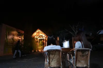 two women sitting in chairs in front of a house at night at Hotel near the clock tower in Arusha