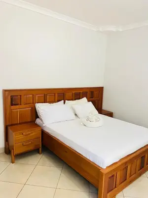 a bedroom with a wooden bed with white sheets at Aviator Safari bnb in Arusha