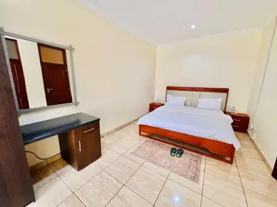 a bedroom with a bed and a desk and a window at JJ Comfort Homes in Arusha