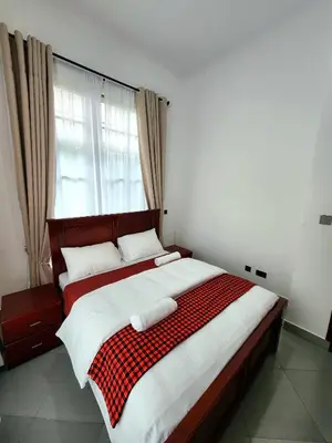 a bedroom with a bed with a red and white blanket at Karibu Haven Apartments in Arusha