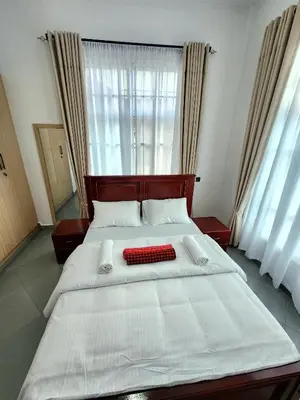 a bedroom with a large white bed with a red pillow at Karibu Haven Apartments in Arusha
