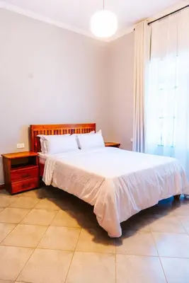 a bedroom with a large white bed and a window at LEGIT HOUSE Arusha in Arusha