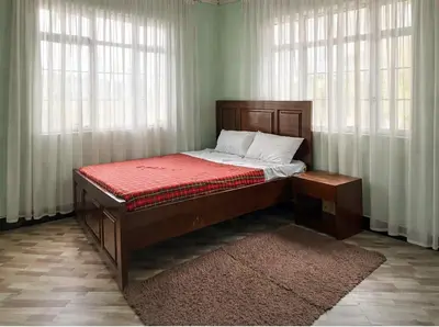 a bed sitting in a room with windows at Oltare House in Makuyuni