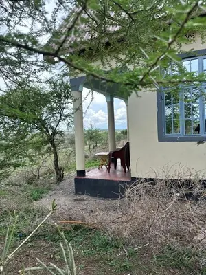 a table and a chair in front of a house at Oltare House in Makuyuni