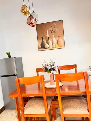 a dining room table with two chairs and a refrigerator at Lululiving Homes in Arusha