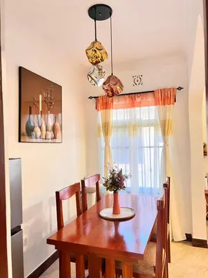 a dining room with a wooden table and a window at Lululiving Homes in Arusha