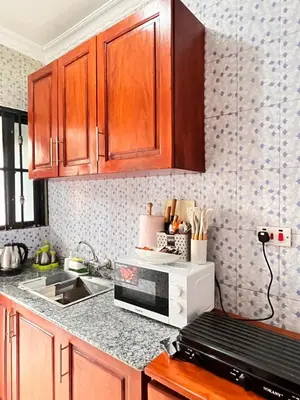 a kitchen with wooden cabinets and a microwave at Lululiving Homes in Arusha