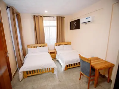 a room with two beds and a table and a desk at Kiliscape Abode in Uru