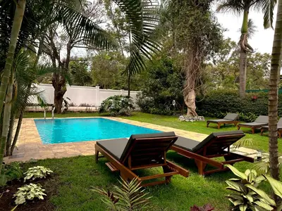 a swimming pool with two lounge chairs and a table at Brubru Lodge in Moshi