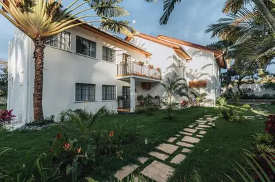 a white house with a palm tree in the yard at Brubru Lodge in Moshi