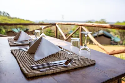 a table with napkins and utensils on a wooden table at Pembeni Rhotia in Karatu