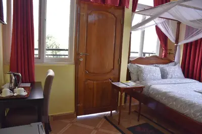 a bedroom with a canopy bed and a table and window at East Point Hotel Moshi in Moshi