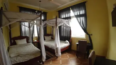 a bedroom with two beds and a canopy bed at East Point Hotel Moshi in Moshi