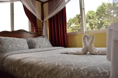 a bed with two shoes on it in front of windows at East Point Hotel Moshi in Moshi