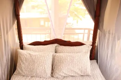 a bed with white pillows in a room with a window at East Point Hotel Moshi in Moshi