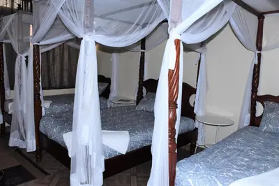 a bedroom with two beds with white drapes at East Point Hotel Moshi in Moshi