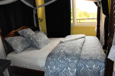 a bedroom with a bed with pillows and a window at East Point Hotel Moshi in Moshi