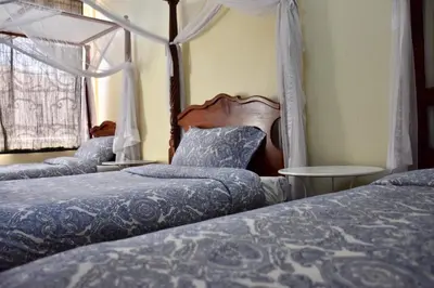 two beds in a bedroom with a woman sticking her head out the window at East Point Hotel Moshi in Moshi