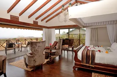 a bedroom with a bed and a balcony with a piano at Ngorongoro Oldeani Mountain Lodge in Oldeani