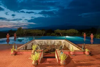 a pool at night with potted plants around it at Ngorongoro Oldeani Mountain Lodge in Oldeani