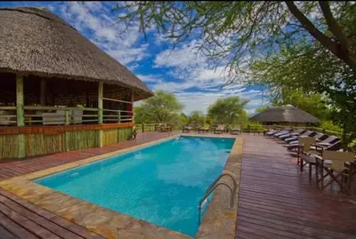 a swimming pool with chairs and a pavilion at Mbali Mbali Tarangire River Camp in Kwa Kuchinia
