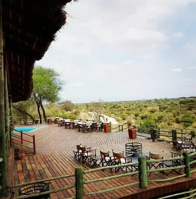 a wooden deck with tables and chairs and a pool at Mbali Mbali Tarangire River Camp in Kwa Kuchinia