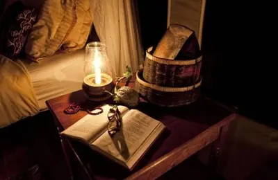 a table with a candle and a hat and books at Mbali Mbali Tarangire River Camp in Kwa Kuchinia